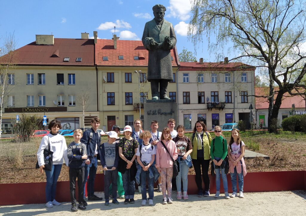 Zdjęcie zrobione grupie uczniów wraz z nauczycielami pod pomnikiem Reymonta