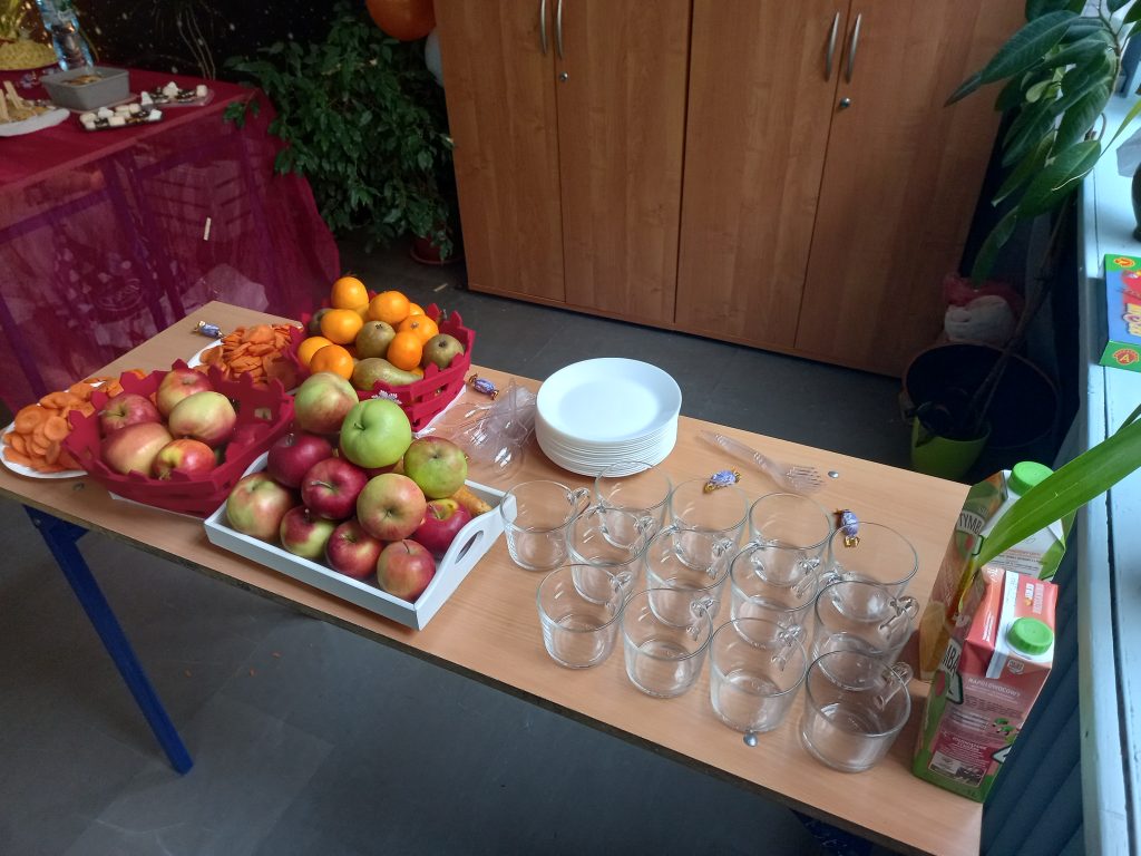 zdjęcie stołu z jabłkami, marchewkami, mandarynkami, gruszkami napojami i szklankami