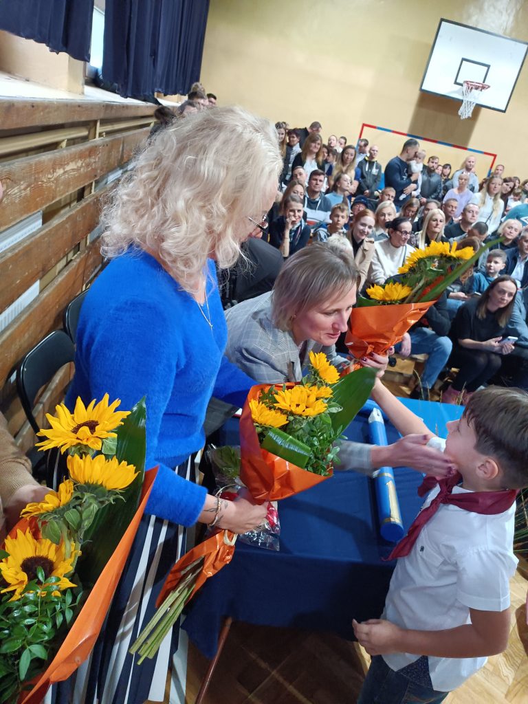 zdjęcie jak dzieci wręczają kwiaty Panią Dyrektor