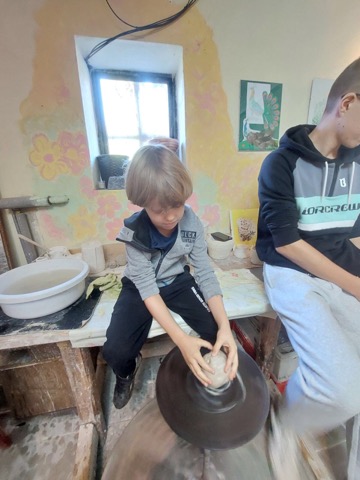 zdjęcie przedstawia chłopca podczas robienia naczynia z gliny