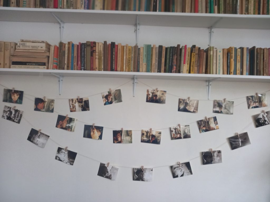zdjęcie przedstawia książki na półkach i zdjęcia przywieszone do sznureczka.