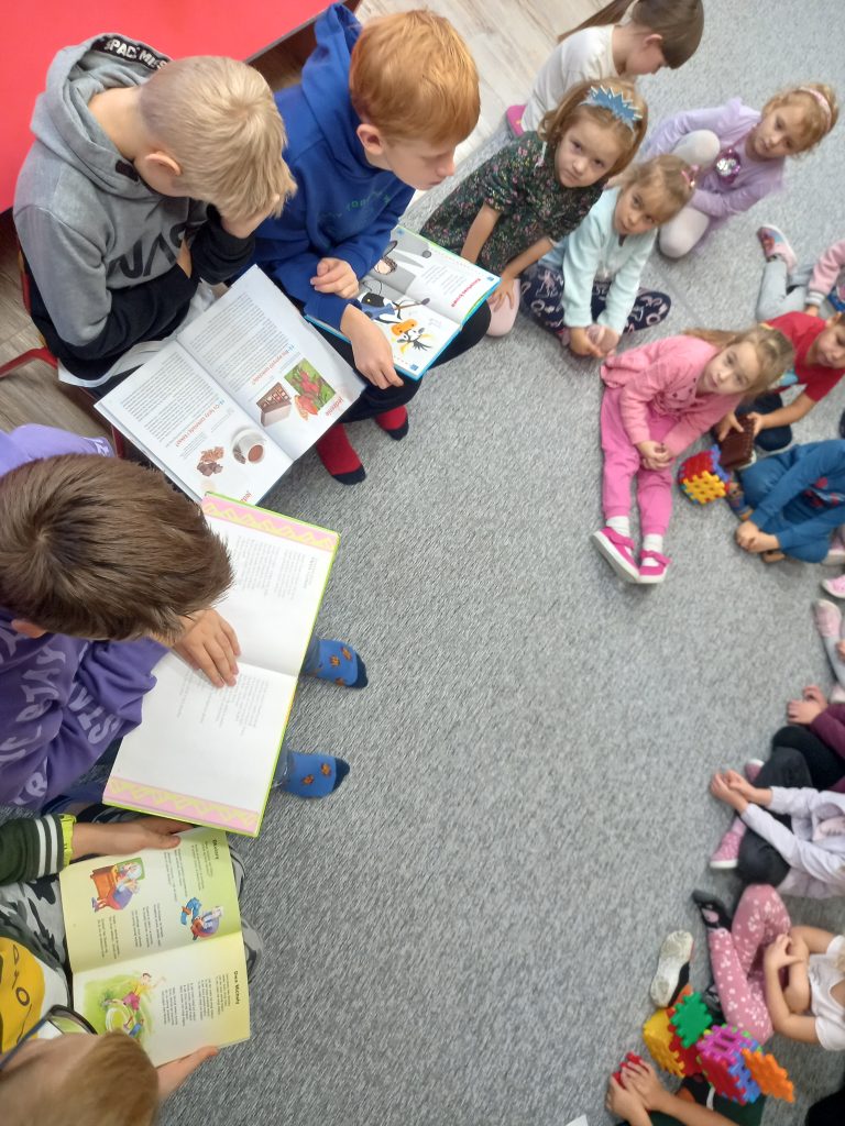 na zdjęciu uczniowie czytają wiersze przedszkolakom 