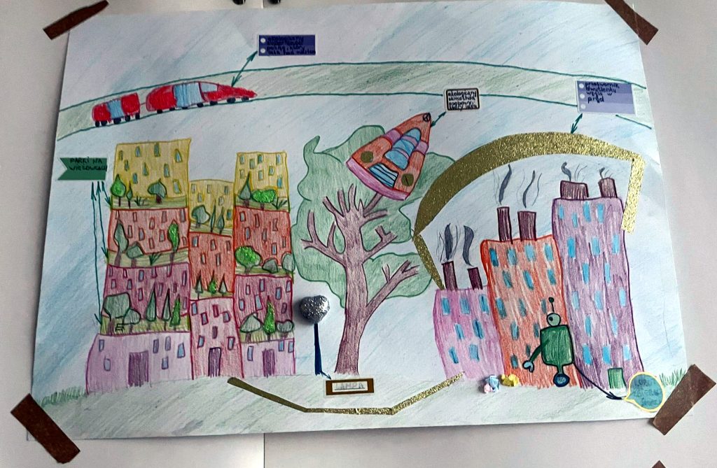 Zdjęcie przedstawia rysunek  nowoczesnego miasta z latającymi pojazdami i nowoczesnym transportem. 