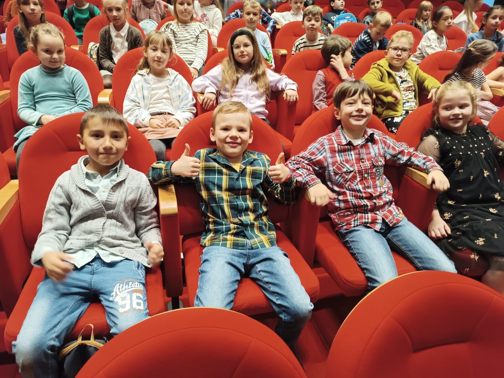 zdjęcie uczniów w czerwonych  fotelach w teatrze
