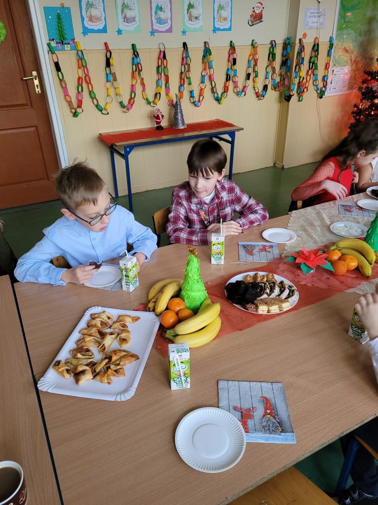 dzieci siedzą przy świątecznym stole z łakociami