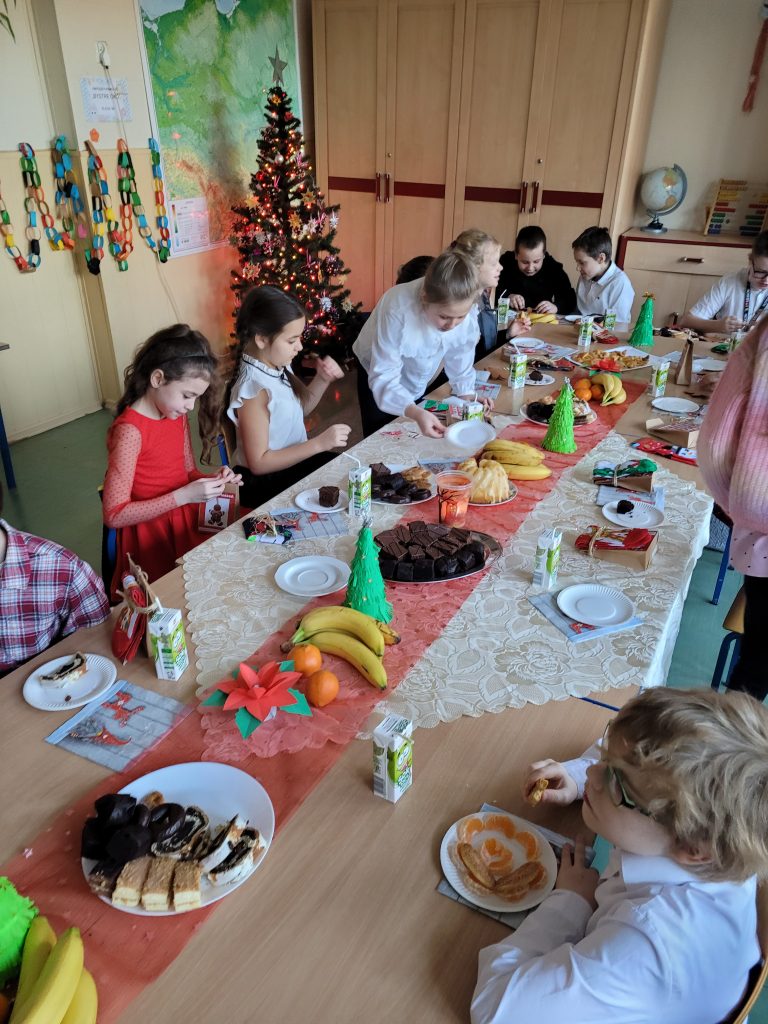 dzieci siedzą przy świątecznym stole z łakociami