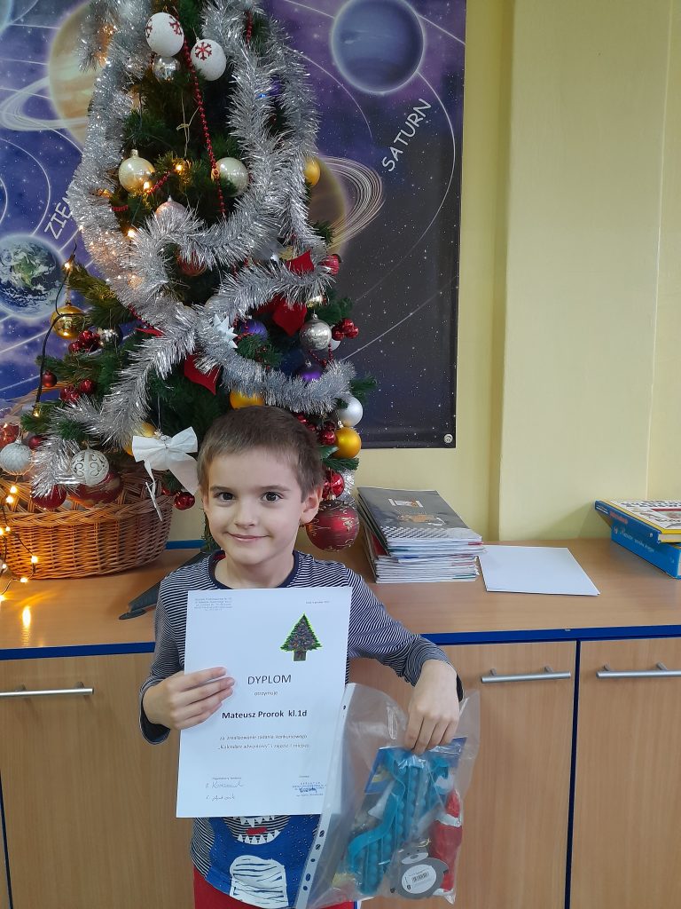 na zdjęciu dziecko trzyma dyplom i upominki za zajęcie pierwszego miejsca.