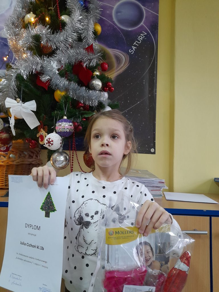 na zdjęciu dziecko trzyma dyplom i upominki za zajęcie pierwszego miejsca.
