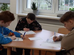 zdjęcie przedstawia uczniów piszących zadania konkursowe
