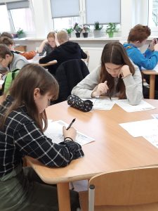 zdjęcie przedstawia uczniów piszących zadania konkursowe