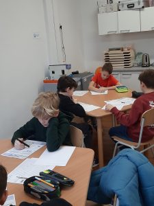 zdjęcie przedstawia uczniów piszących zadania konkursowe
