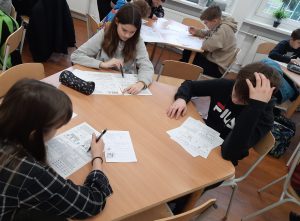 zdjęcie przedstawia uczniów piszących zadania konkursowe