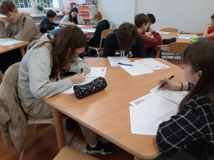 zdjęcie przedstawia uczniów piszących zadania konkursowe