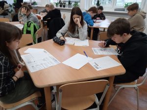 zdjęcie przedstawia uczniów piszących zadania konkursowe