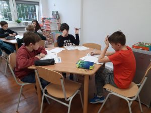 zdjęcie przedstawia uczniów piszących zadania konkursowe