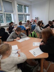 zdjęcie przedstawia uczniów piszących zadania konkursowe