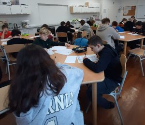 zdjęcie przedstawia uczniów piszących zadania konkursowe