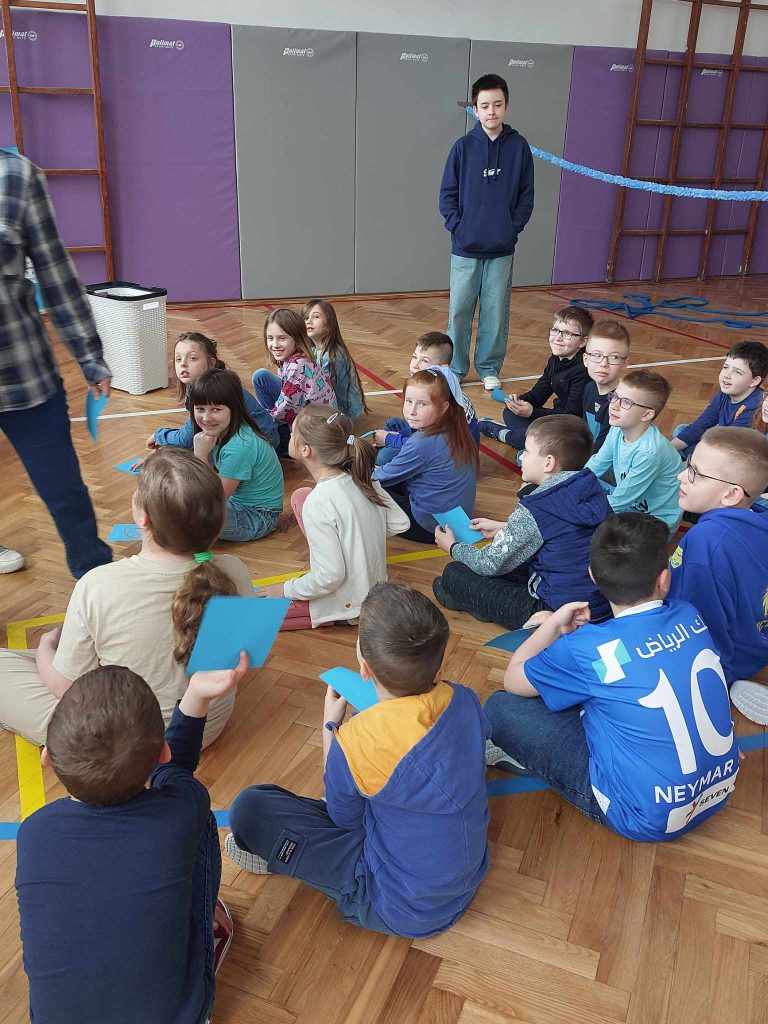 zdjęcie przedstawia jak uczniowie siedzą na podłodze