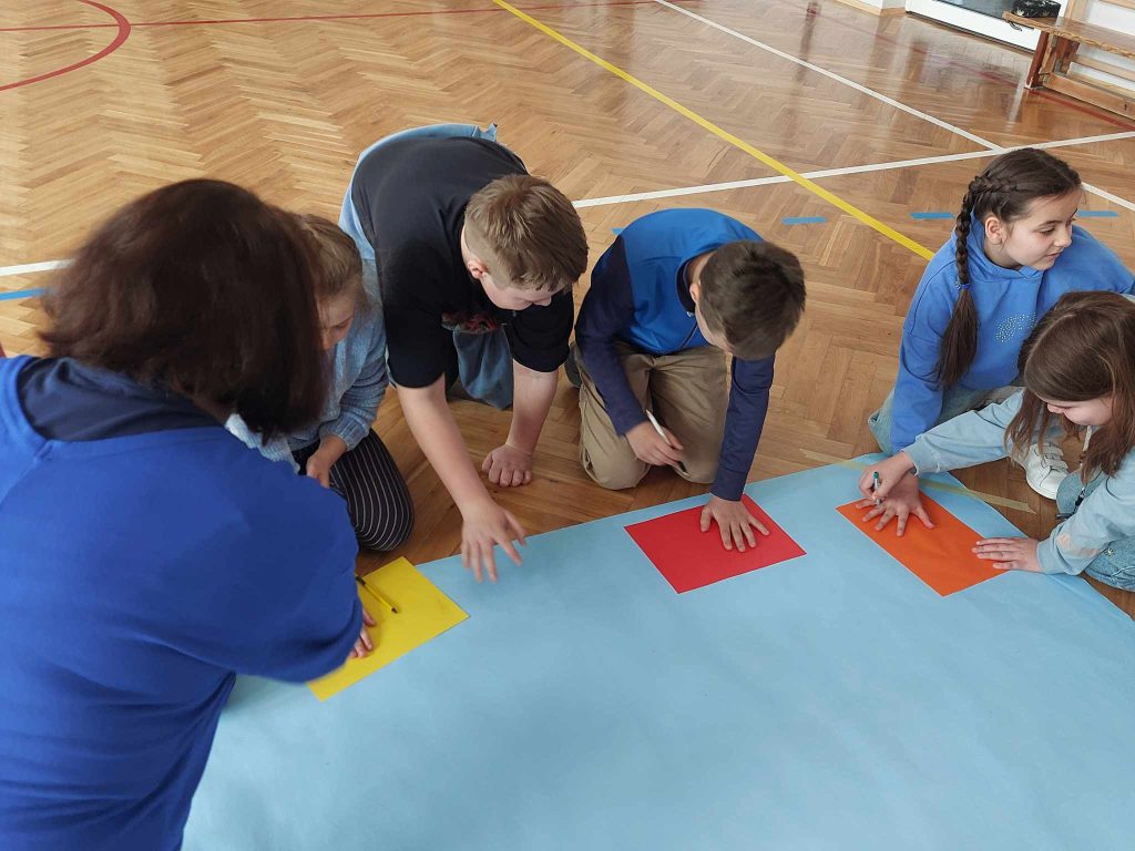 zdjęcie przedstawia jak dzieci wykonują pracę na niebieskim papierze