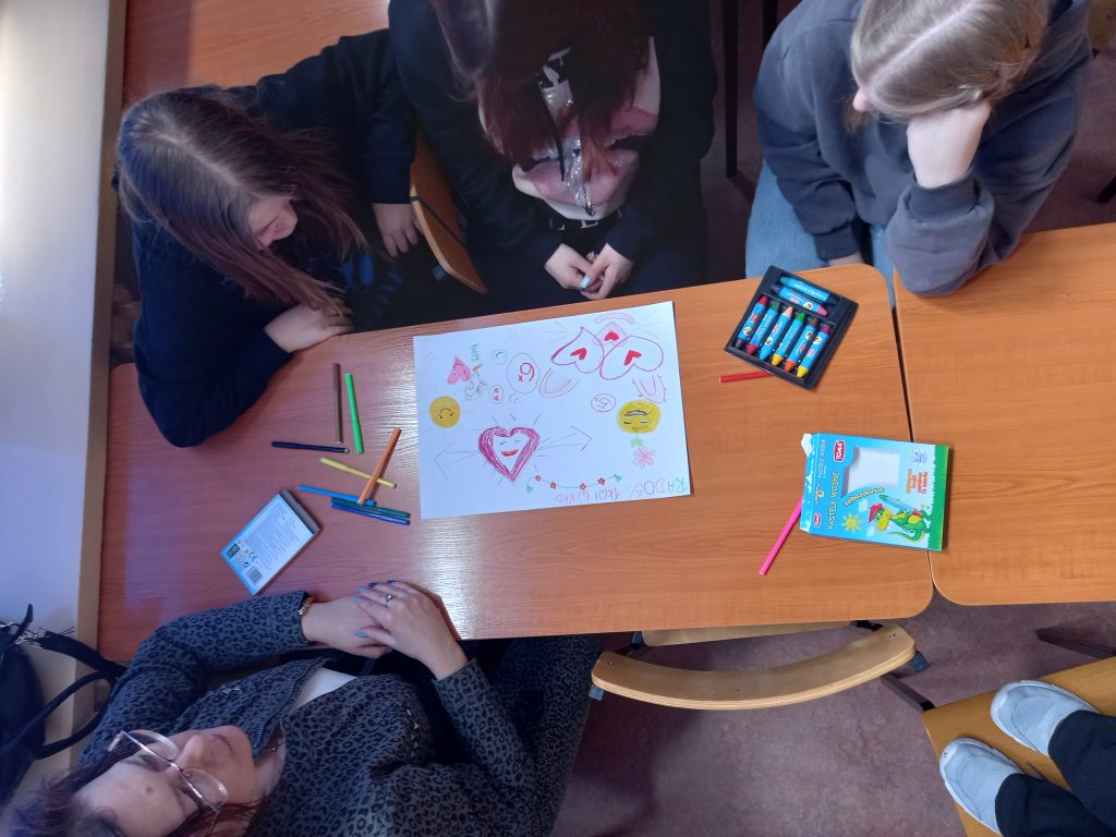 Zdjęcie przedstawia jak uczennice pracują w ławkach nad plakatem.