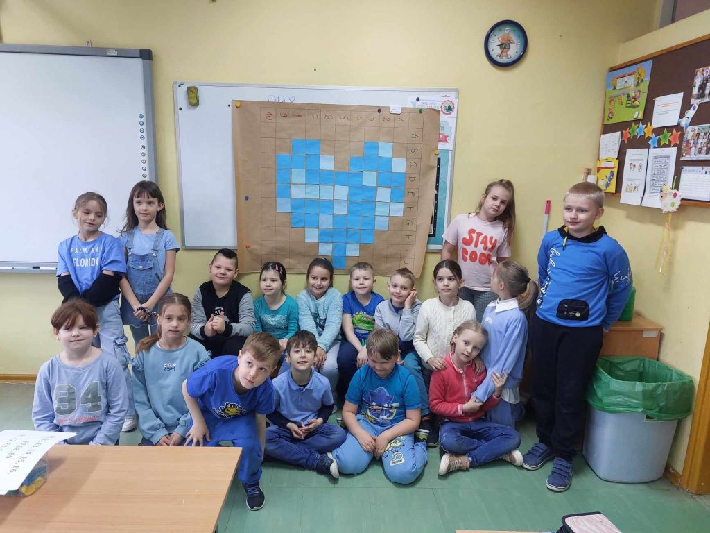 zdjęcie przedstawia zdjęcie grupowe dzieci na tle niebieskiego serca