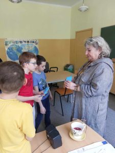 Zdjęcie przedstawia jak uczniowie dają niebieską kopertę z hasłem Pani Dyrektor