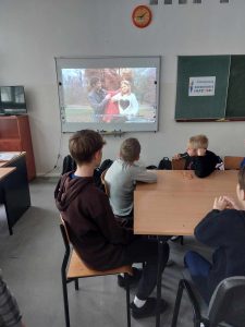 zdjęcie przedstawia jak uczniowie siedzą w ławkach i oglądają film