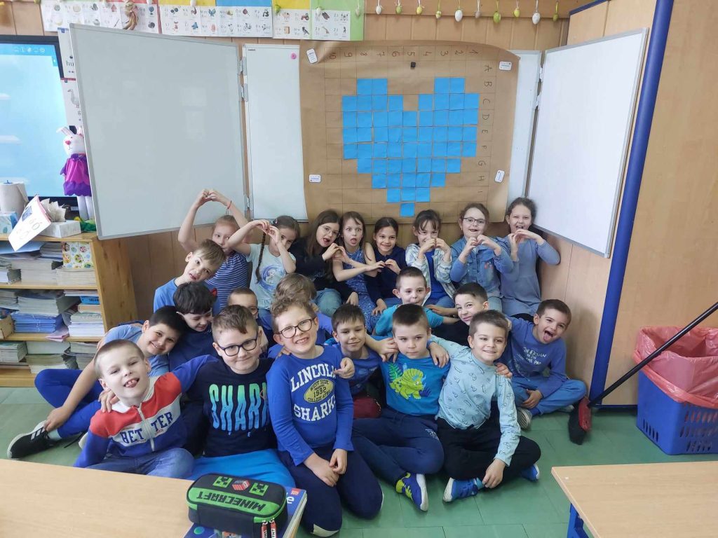 zdjęcie przedstawia zdjęcie grupowe dzieci na tle niebieskiego serca