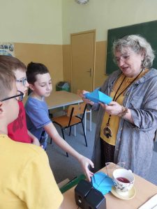 Zdjęcie przedstawia jak Pani Dyrektor czyta hasło motywacyjne z niebieskiej koperty