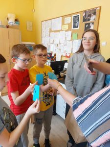 Zdjęcie przedstawia jak uczniowie trzymają niebieskie koperty z hasłem motywacyjnym o autyźmie