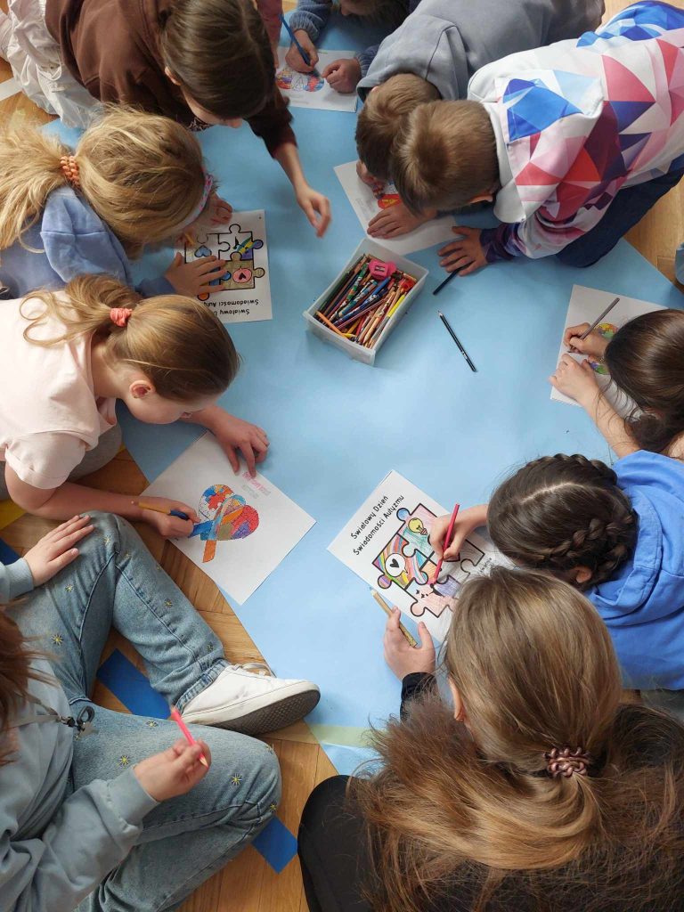 zdjęcie przedstawia jak uczniowie malują na niebieskiej kartce