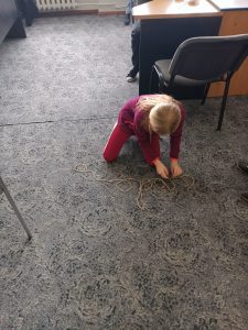 Uczennica układa napis WODA ze sznurka.