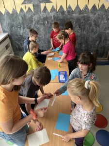 Zdjęcie przedstawia dzieci czytające krótkie hasełka na kartkach