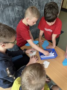 Zdjęcie przedstawia jak uczniowie losują hasła z niebieskiego koszyczka