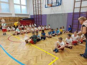 uczniowie na zdjęciu są podzieleni na grupy, siedzą na podłodze
