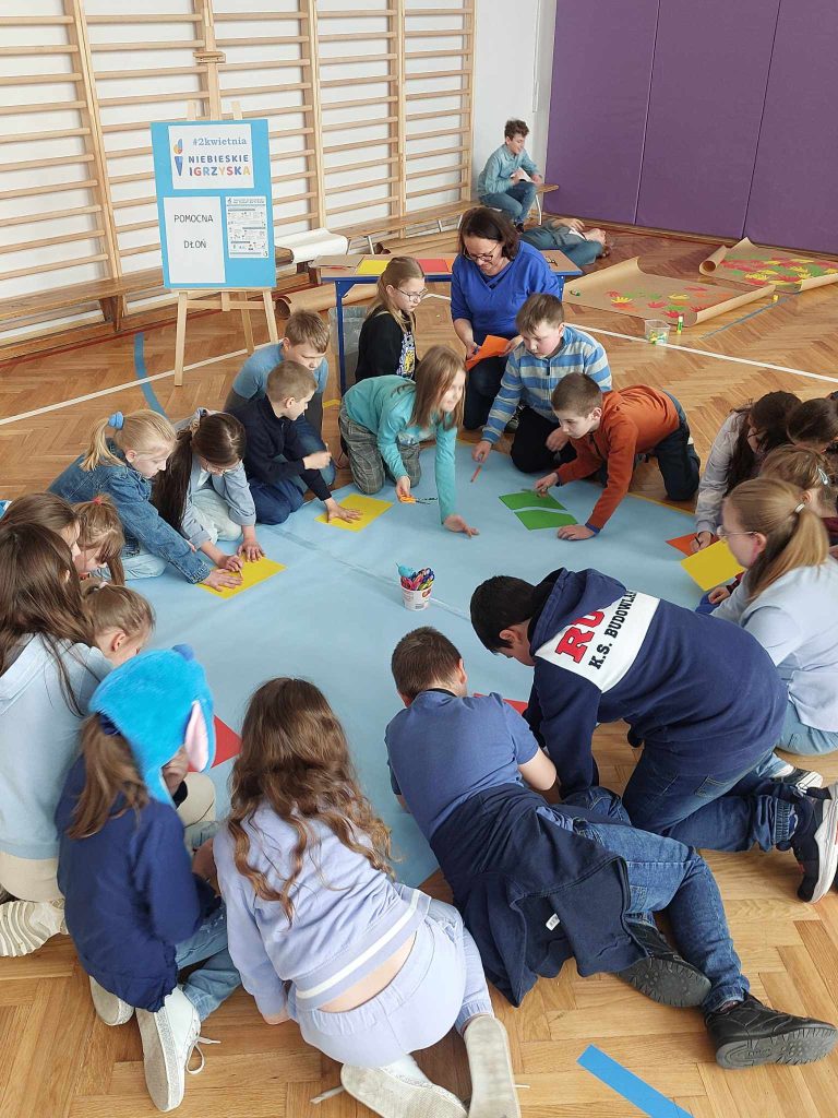 zdjęcie przedstawia jak uczniowie wykonują prace na podłodze- origami