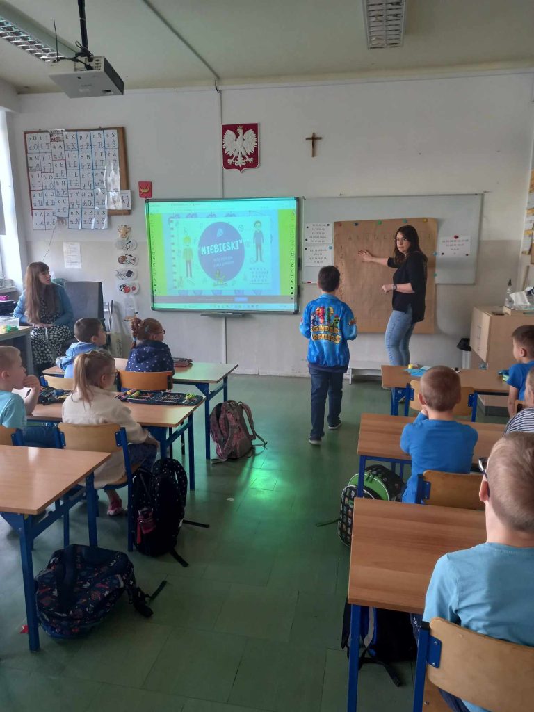 zdjęcie przedstawia jak pedagog tłumaczy coś dzieciom