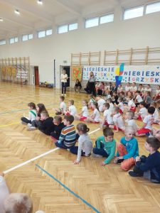 uczniowie na zdjęciu siedzą na podłodze podzieleni na drużyny