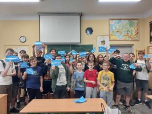 Zdjęcie przedstawia uczniów trzymających niebieskie koperty