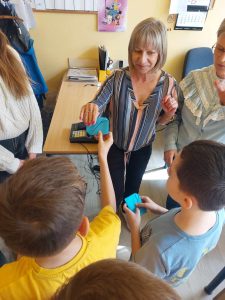 Zdjęcie przedstawia jak uczniowie dają koperty z hasłami pracownikom