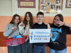 Zdjęcie przedstawia jak uczniowie trzymają plakat z napisem niebieskie igrzyska i koszyk z niebieskimi kopertami