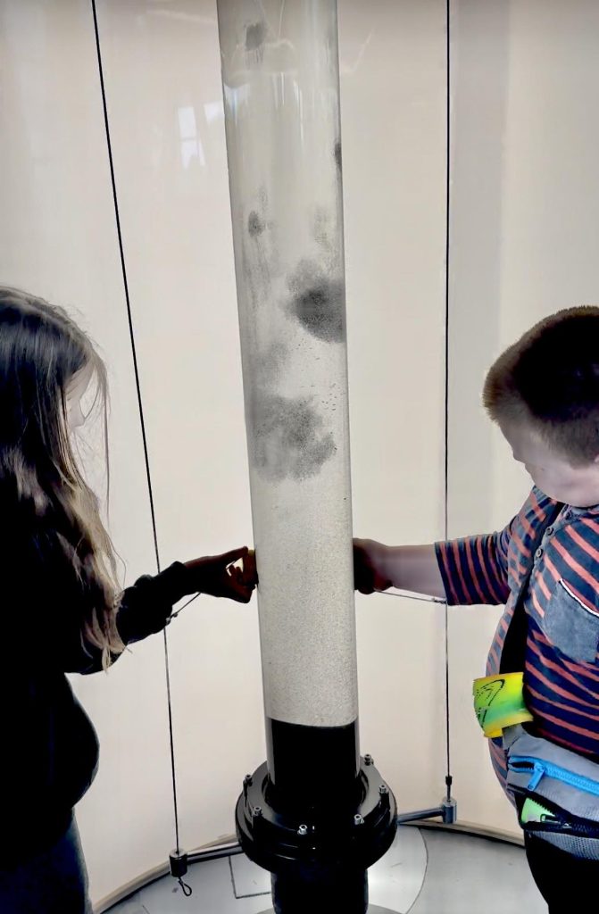 Zdjęcie przedstawia chłopca i dziewczynkę bawiących się opiłkami magnesu