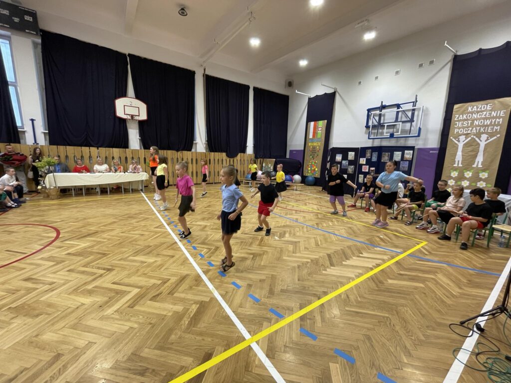 grupa dzieci tańczy na sali gimnastycznej ubrana na kolorowo