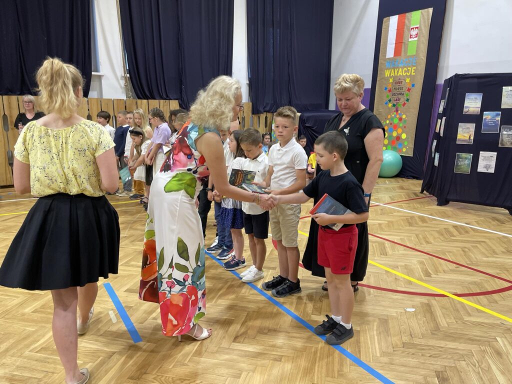 grupa uczniów ma wręczane nagrody na środku sali gimnastycznej