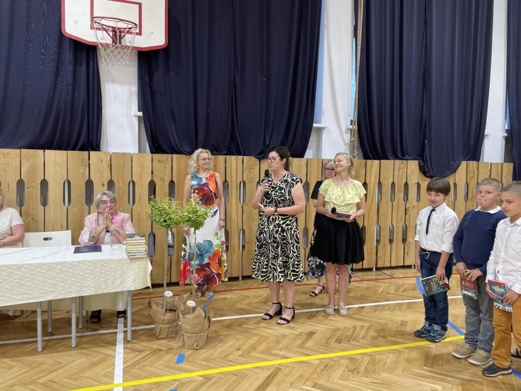 grupa uczniów ma wręczane nagrody na środku sali gimnastycznej