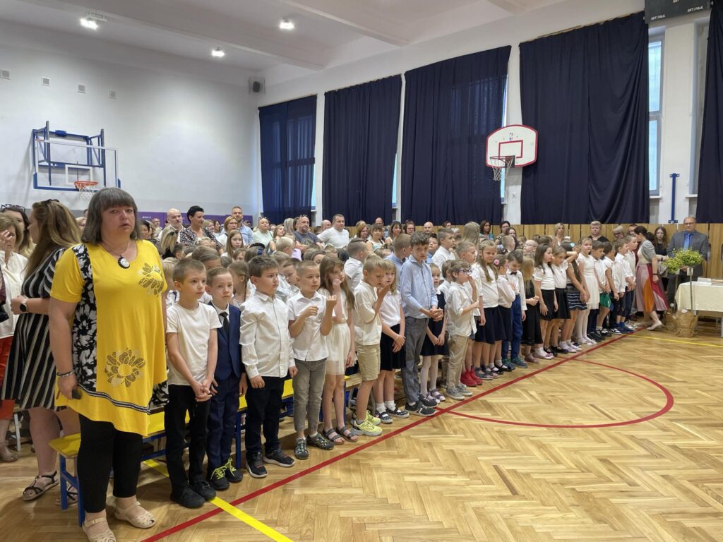 zdjęcie grupy uczniów i rodziców i nauczycieli oglądających uroczyste zakończenie