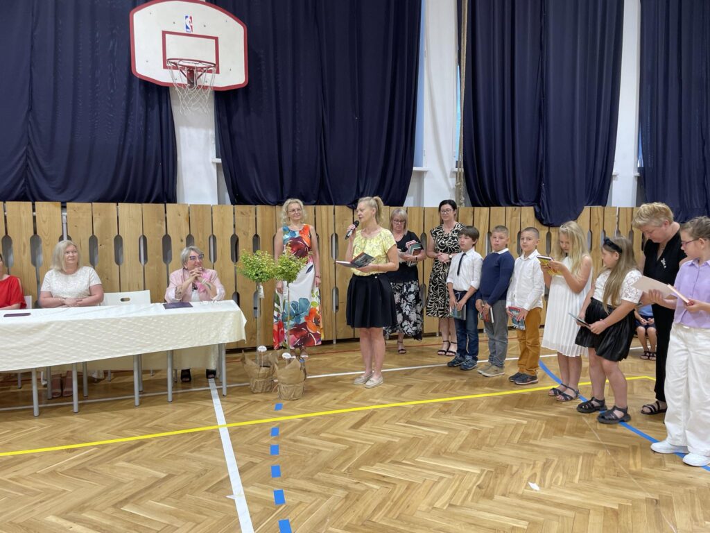 grupa uczniów ma wręczane nagrody na środku sali gimnastycznej