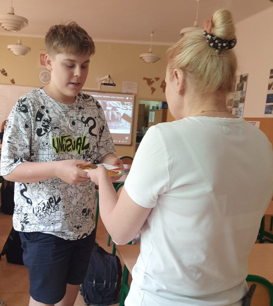 dyplom jest wręczany uczniowi przez nauczycielkę