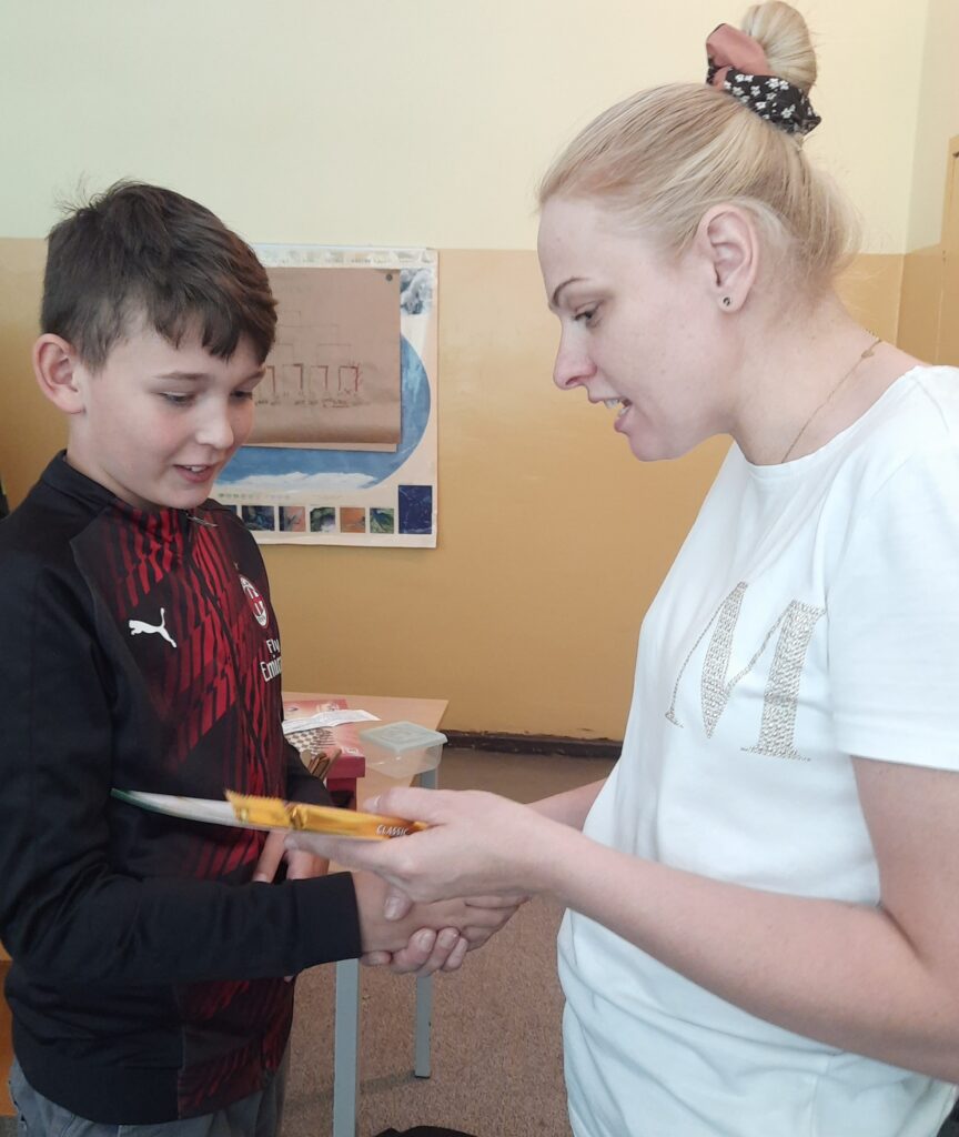 dyplom jest wręczany uczniowi przez nauczycielkę