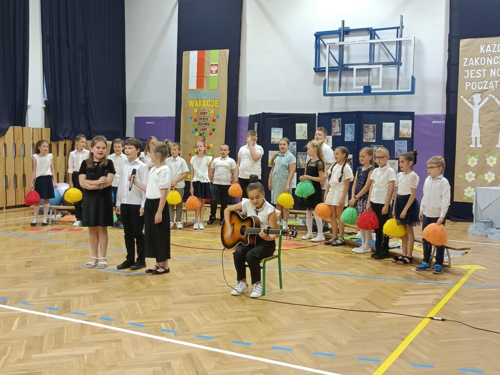 dzieci śpiewają, uczennica gra na  gitarze